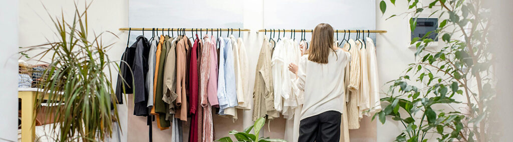 A lady sifting through a rack of clothing to envision her social media marketing experience.