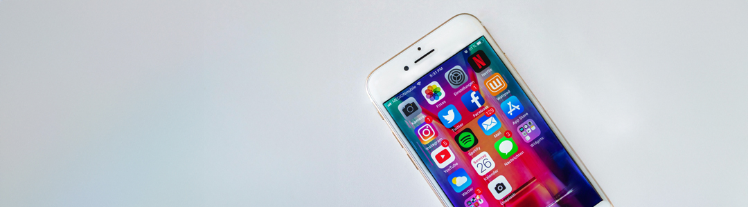 A phone sitting on a white counter top open with apps to automate her social media.